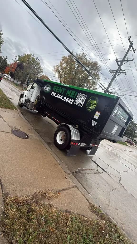 Empire Dumpsters truck delivering a roll-off dumpster wrapped with a green Hulk graphic