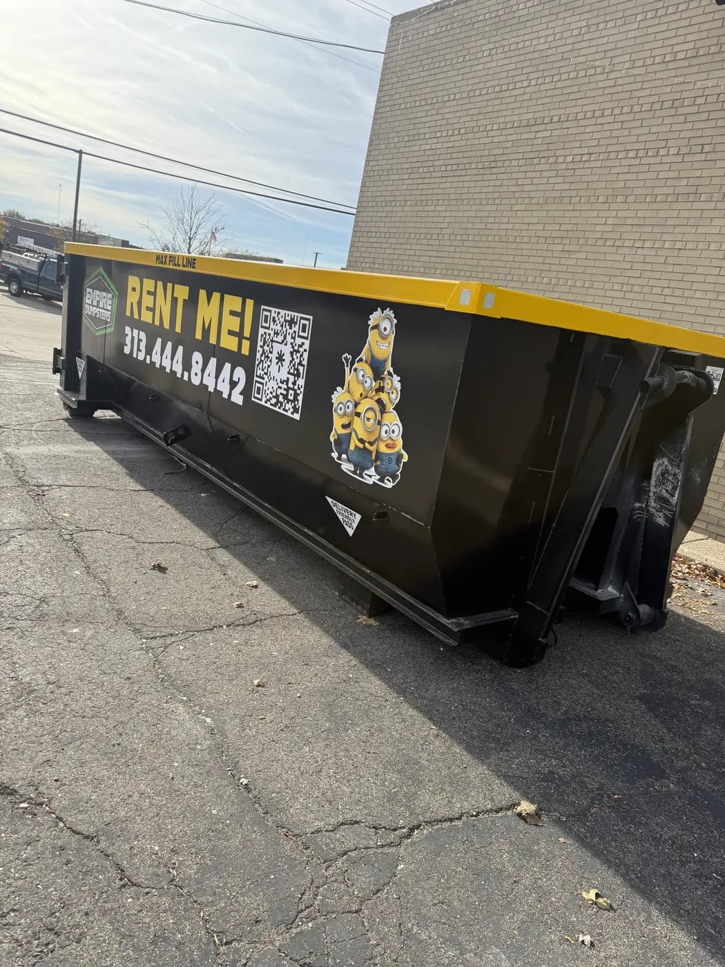 Empire Dumpsters roll-off with a yellow rail and a stack of Minions characters on the side
